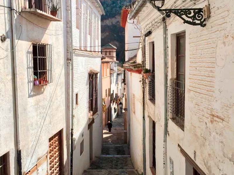 Stradina imbiancata dell'Albaicín con l'Alhambra sullo sfondo